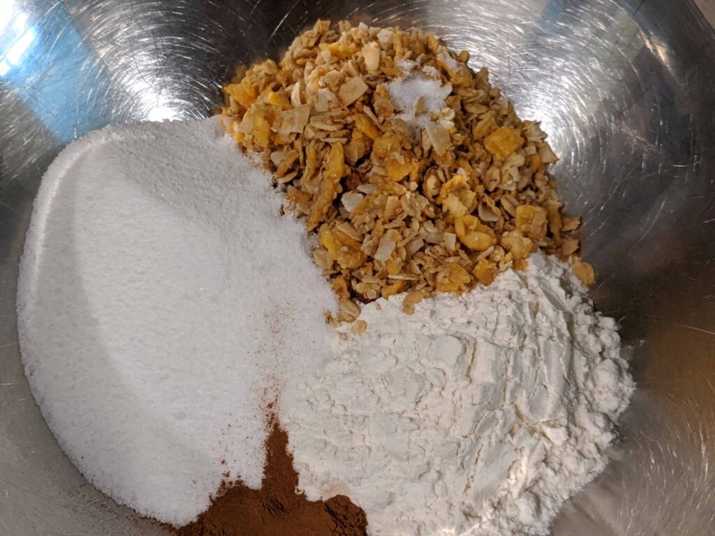 flour, granola, sugar, cinnamon in a silver bowl