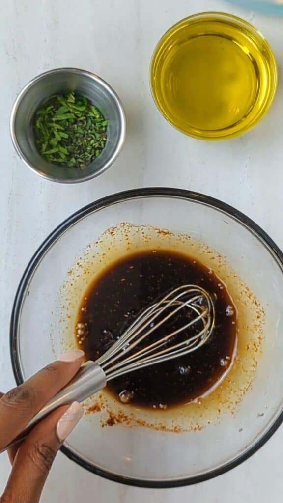 balsamic vinegar with spices in a bowl, olive oil in a small cup, fresh herbs in a small cup